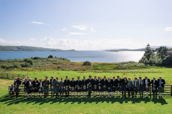 Bridal party in long line in front of Loch Melfort