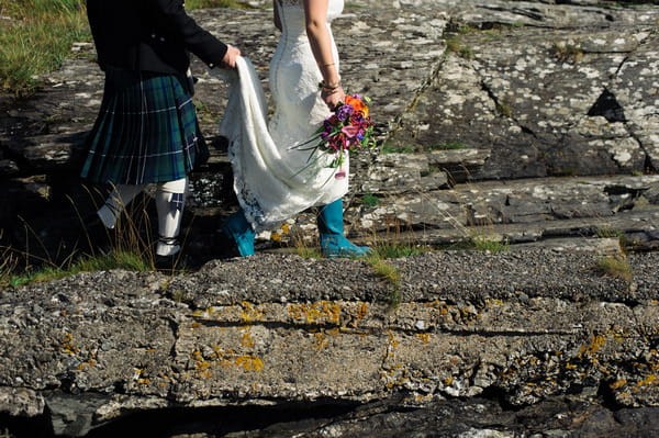 Bride in wellies walking across rocks