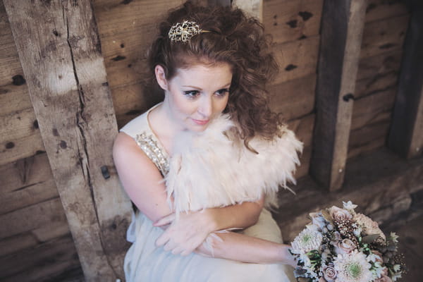 Bride with feather shrug sitting on floor