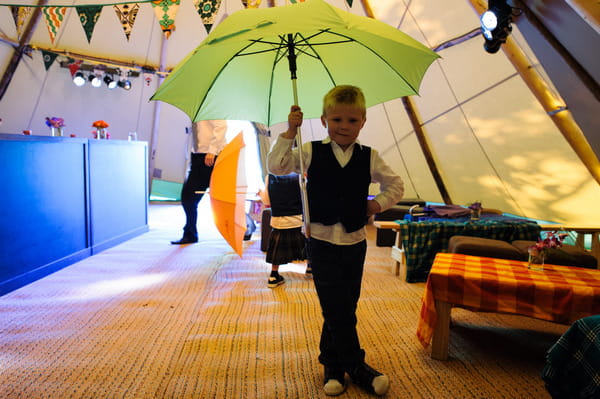 Young boy at wedding holding umbrella