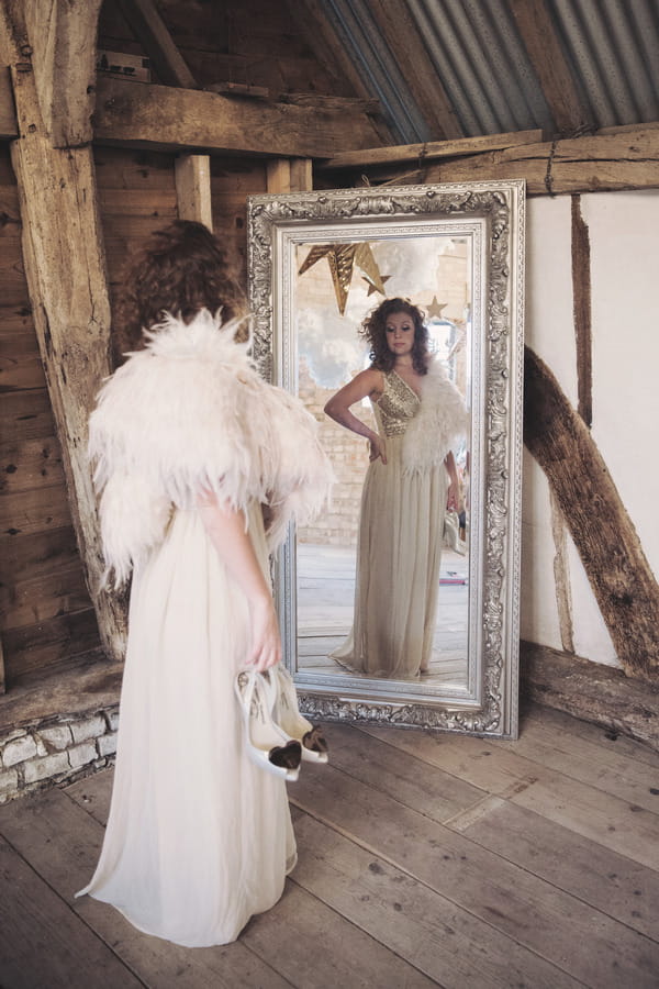 Bride with feather shrug looking in mirror