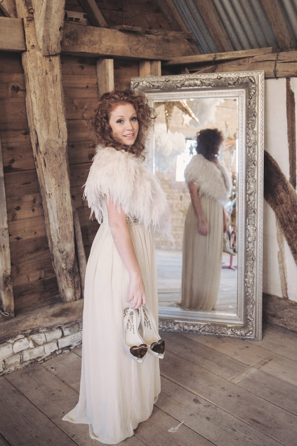 Bride holding shoes looking over shoulder