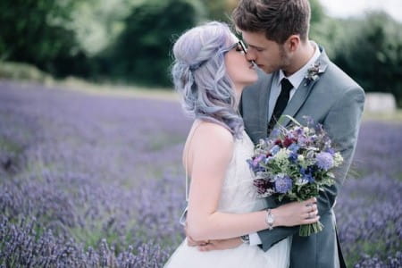 Bride with purple hair about to kiss groom in field of lavender - Picture by Lucie Watson Photography