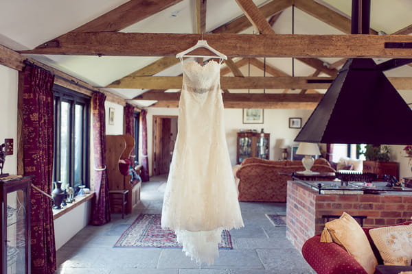 Wedding dress hanging from ceiling beam
