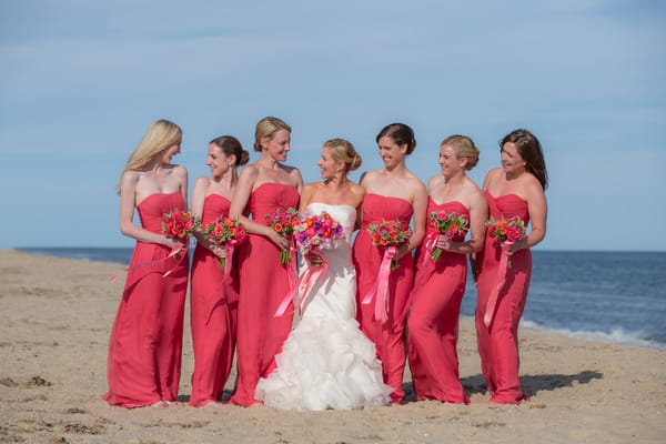 Bride and bridesmaids in pink dresses on beach