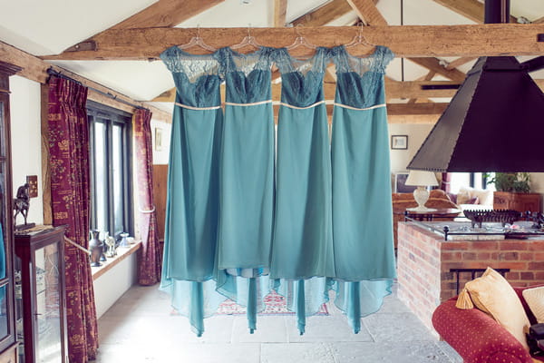 Light blue bridesmaid dresses hanging from ceiling beam