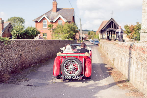 Bride and groom driving to reception in vintage MG TC 1947 wedding car