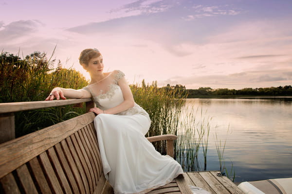 Bride on bench by lake