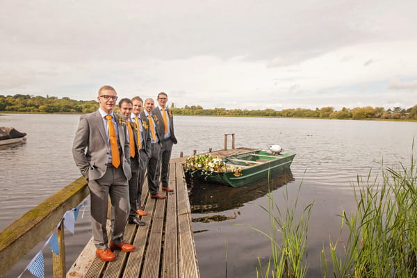 Row of groomsmen by lake