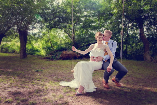 Bride and groom sitting on rope swing