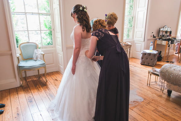 Bridesmaid helping bride with wedding dress