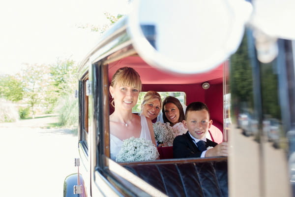 Bride, bridesmaids and pageboy in back of wedding car