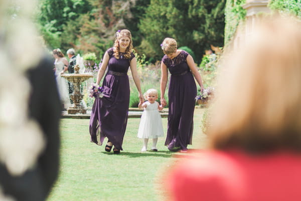 Bridesmaids leading flower girl down the aisle