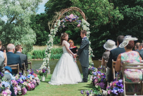 Wedding ceremony by lake at Narborough Hall Gardens