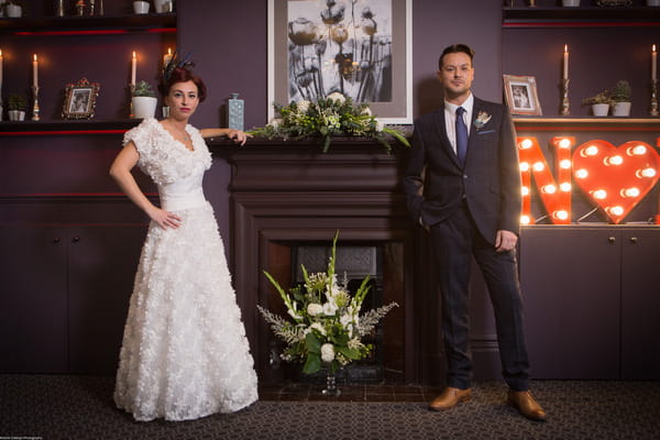 Bride and groom standing by fireplace at The Alverton Hotel