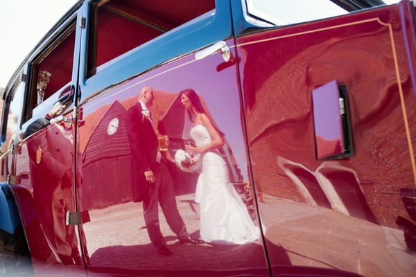 Reflection of bride and groom in door of wedding car