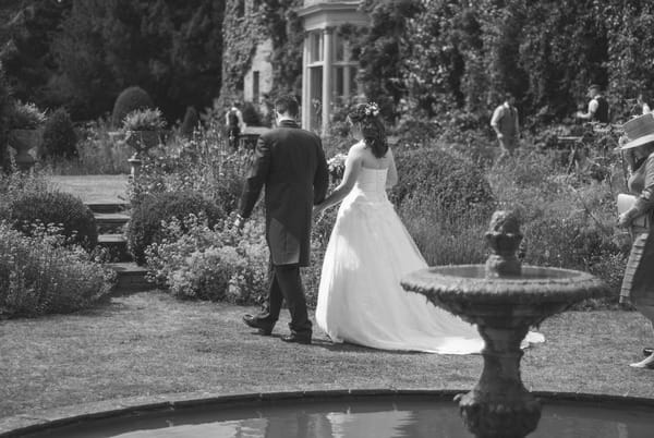 Bride and groom walking past fountain at Narborough Hall Gardens