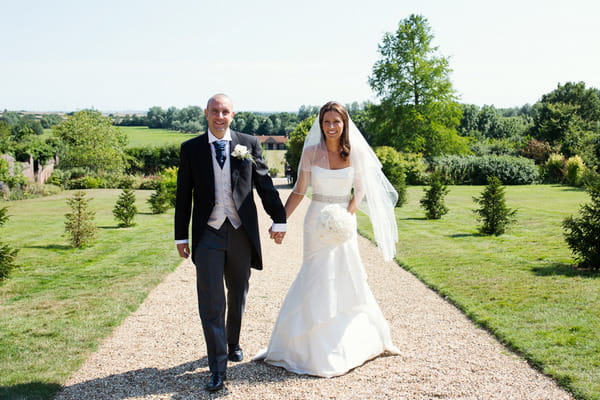 Bride and groom walking up Layer Marney Tower driveway