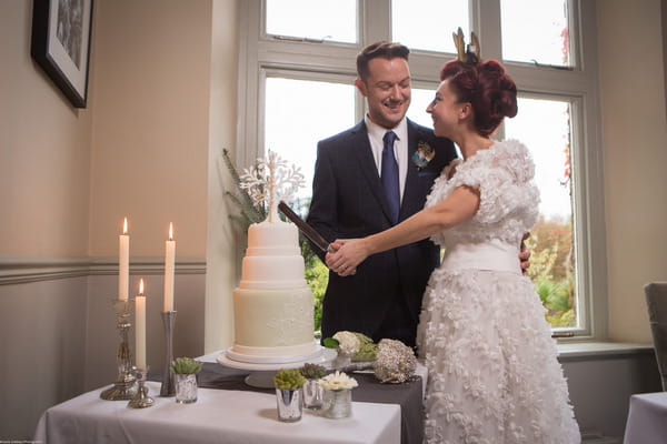 Bride and groom smiling as they cut wedding cake