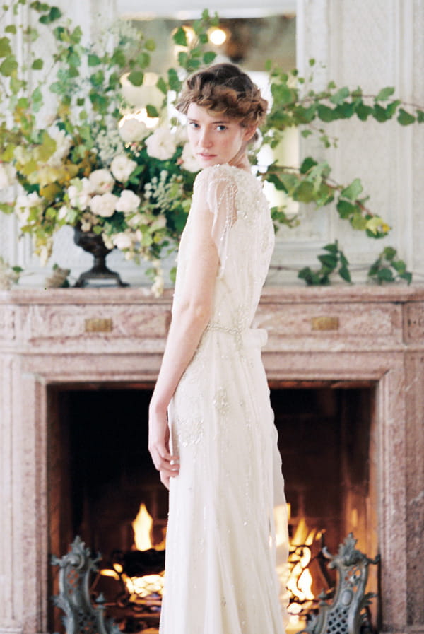 Bride standing in front of fireplace looking over shoulder