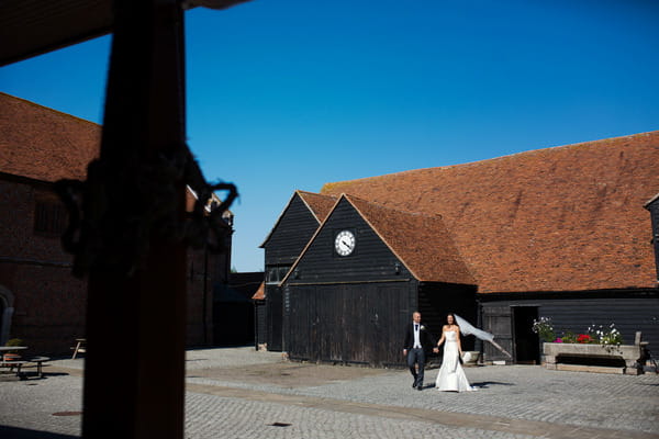Bride and groom walking across courtyard of Layer Marney Tower