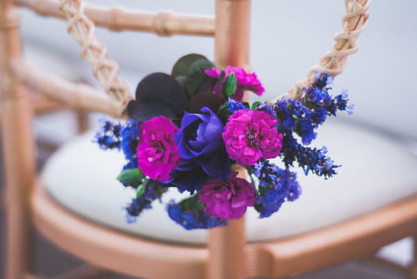 Purple and pink flowers tied to wedding chair