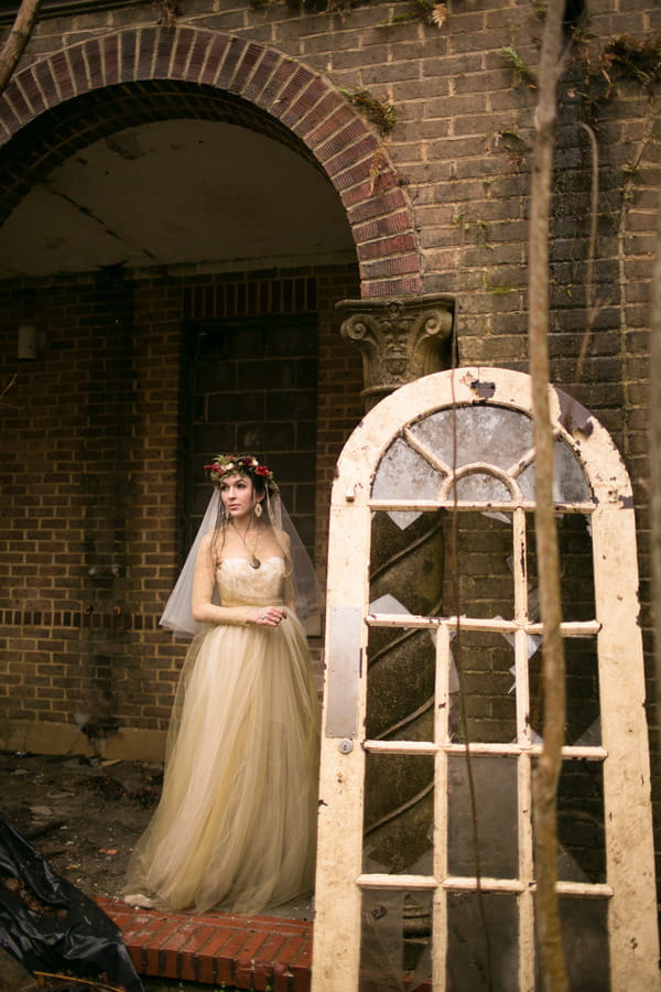 Bride standing by old broken window