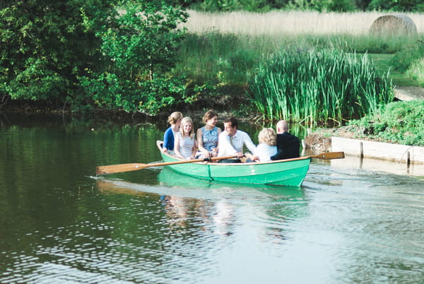 Wedding guests on rowing boat on lake at Narborough Hall Gardens