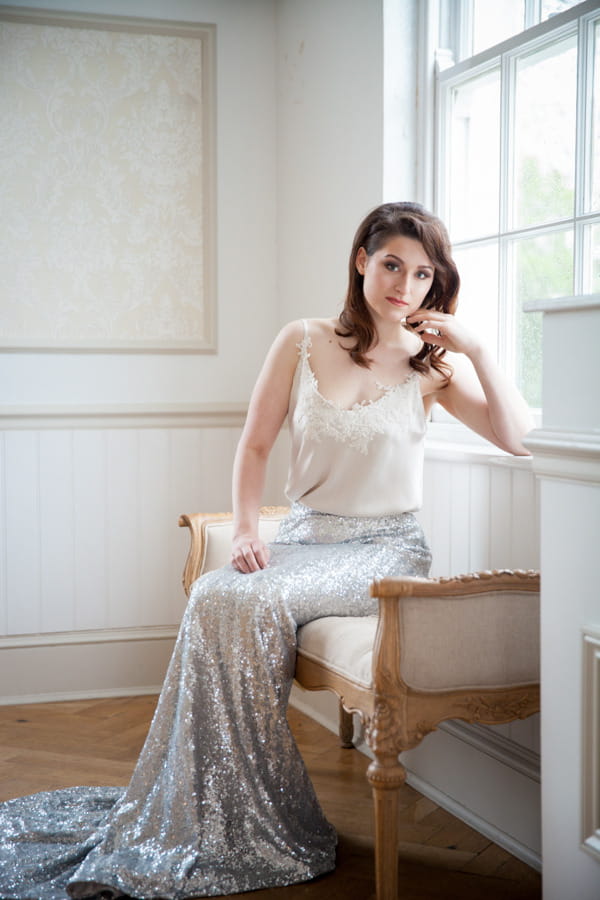 Bride in glittery silver skirt sitting by window