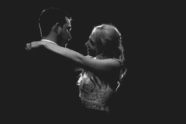 Bride and groom with arms around each other on black background - Picture by Project Valentine