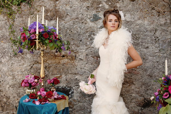 Bride with long dress and shrug standing next to small table