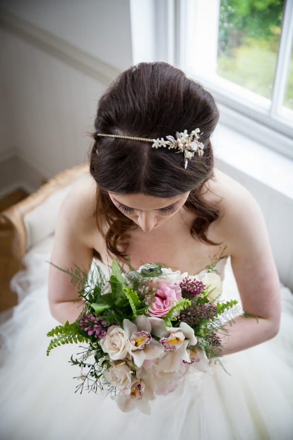 Bride looking down at bouquet to show headband