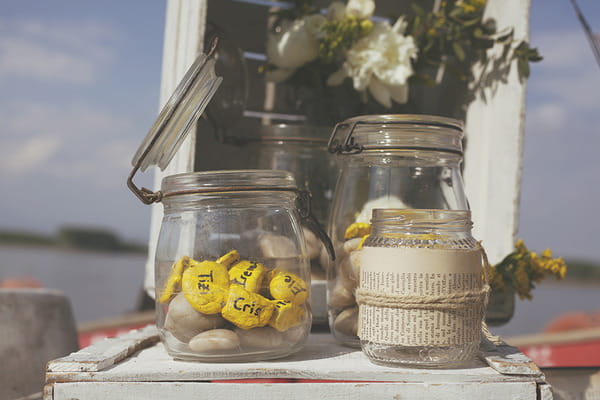 Jar of yellow painted pebbles for wedding place names