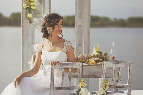 Bride sitting on rustic chair by lake