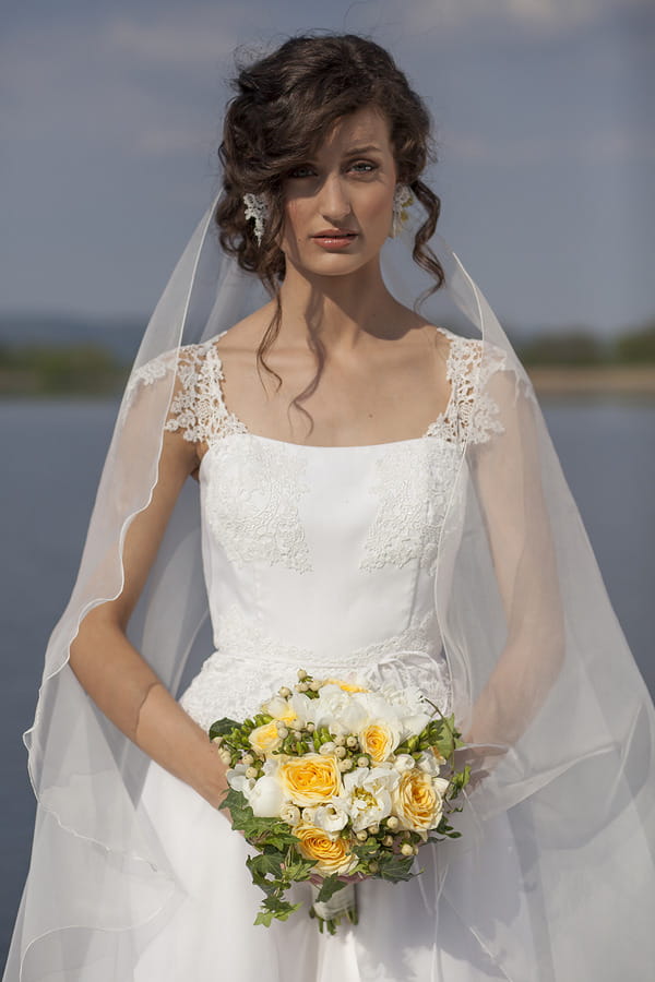 Bride holding spring wedding bouquet of yellow flowers