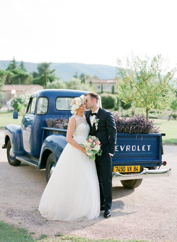 Bride and groom kissing in front of Chevrolet filled with lavender