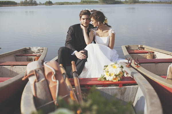 Bride and groom sitting on rowing boat on lake in Italy