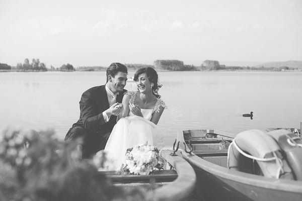 Bride and groom laughing on rowing boat on lake in Italy