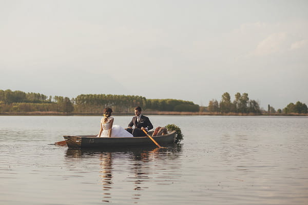 Bride and groom in rowing boat on lake in Italy