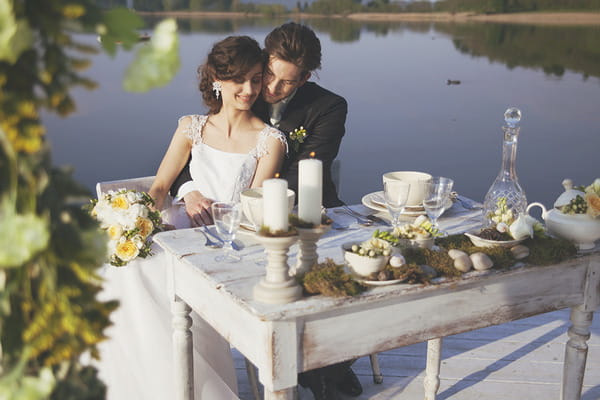Bride and groom sitting at wedding table by Lake of Candia in Italy