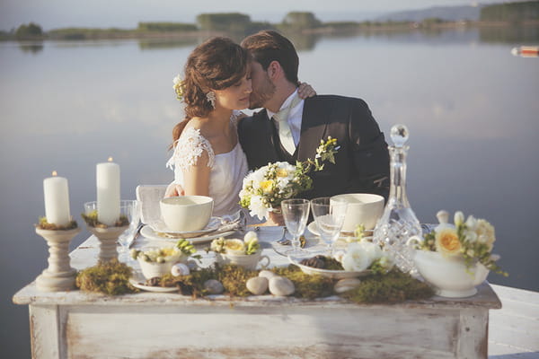Bride and groom sitting at wedding table by lake