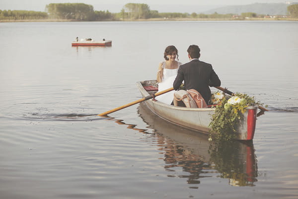 Bride and groom in rowing boat on lake in Italy