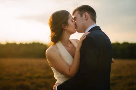 Bride and groom kissing in a field - Picture by Nisha Haq Photography