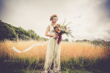 Bride with flower crown and large bouquet standing by field of wheat - Picture by Velvet Storm Photography