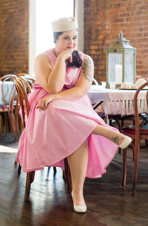 Bride in retro pink wedding dress sitting on chair