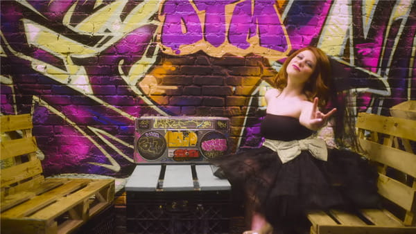 Bride in black wedding dress sitting next to graffiti wall