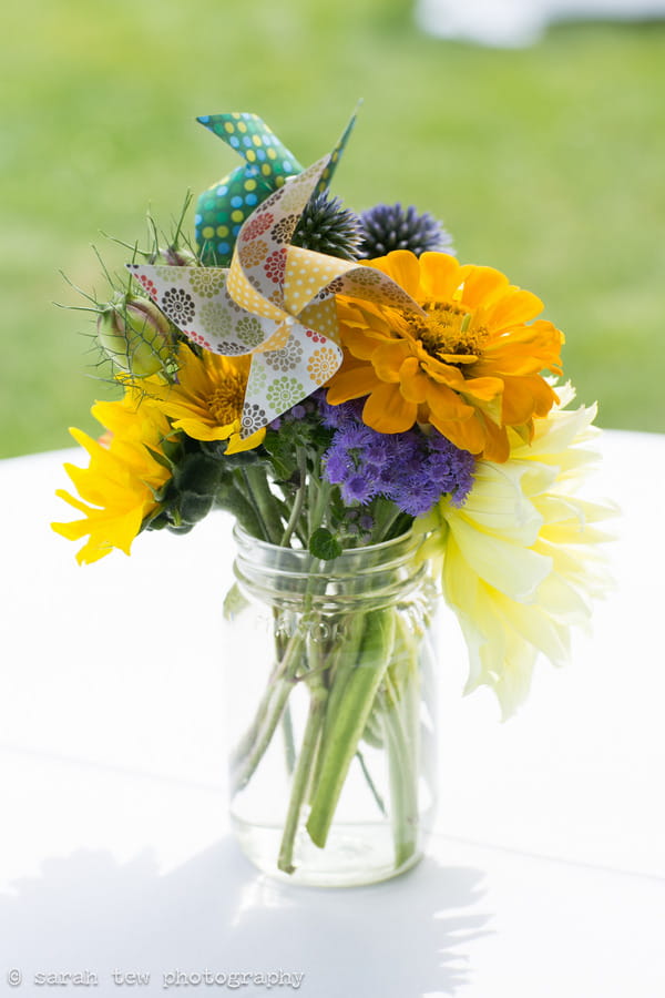 Jar of bright wedding flowers with pinwheel