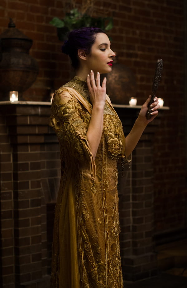 Bride in gold vintage wedding dress looking in mirror