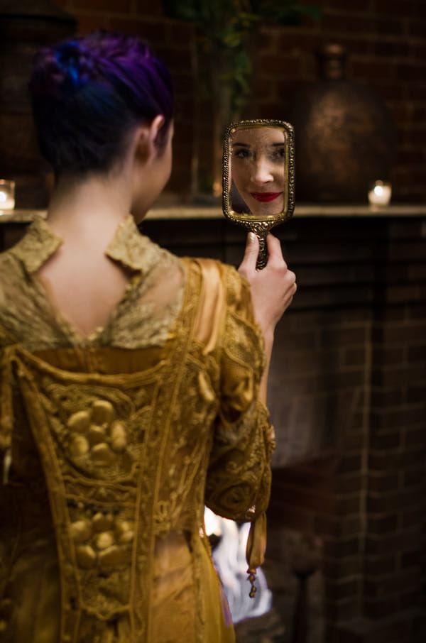 Bride in gold vintage wedding dress looking in mirror