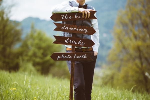 Groom leaning on wedding sign